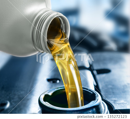 Pouring motor oil into the car engine Pouring motor oil into the car engine 135272123