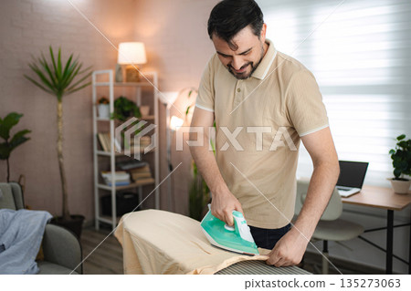 Mid adult man ironing his clothes at home Mid adult man ironing his clothes at home 135273063