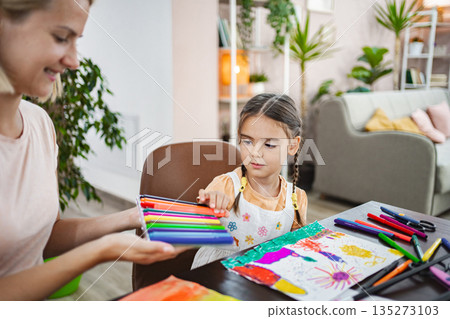 Mother and daughter engage in creative painting at home on a sunny afternoon 135273103