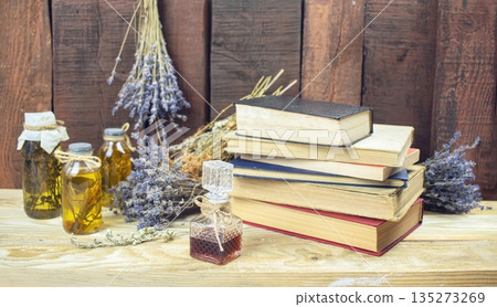 Healing herbal remedies, ancient books, bouquets of mystical herbal potions and candles on wooden background Healing herbal remedies, ancient books, bouquets of mystical herbal potions and candles on wooden background 135273269