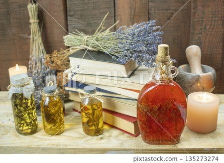 Healing herbal remedies, ancient books, bouquets of mystical herbal potions and candles on wooden background Healing herbal remedies, ancient books, bouquets of mystical herbal potions and candles on wooden background 135273274
