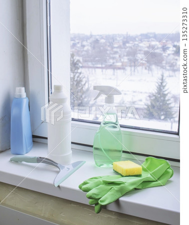 Window cleaning products on a windowsill with a view of a snowy winter 135273310