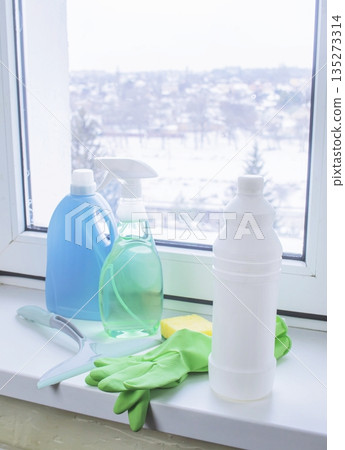Window cleaning products on a windowsill with a view of a snowy winter 135273314