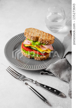 Sandwich with ham, cheese, lettuce and vegetable on a plate on a concrete background Sandwich with ham, cheese, lettuce and vegetable on a plate on a concrete background 135273643