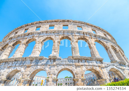 This stunning Roman amphitheatre in Pula stands majestically under a clear blue sky, showcasing its impressive architecture and historical significance as a cultural landmark. 135274534
