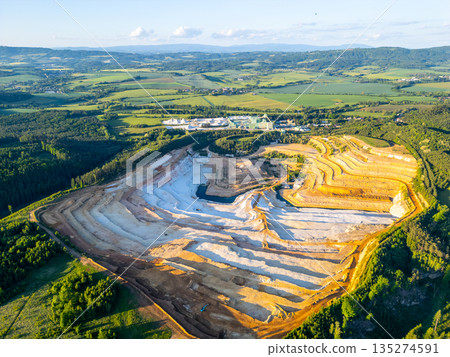 The sandstone quarry in Strelec shows multiple layers of excavated earth and rock. The surrounding fields and hills are visible in the distance under a clear sky. The sandstone quarry in Strelec shows multiple layers of excavated earth and rock. The surrounding fields and hills are visible in the distance under a clear sky. 135274591