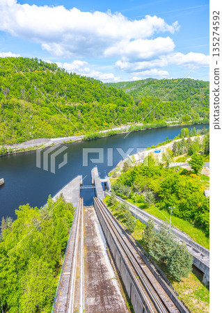 The boat lift at Orlik Dam, located in Czechia, efficiently transports vessels between water levels. Its scenic surroundings include lush greenery and a serene river landscape. 135274592