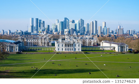Visitors relax in Greenwich Park while modern buildings rise in the background. Trees and open space make it a peaceful retreat in the heart of London on a sunny day. Visitors relax in Greenwich Park while modern buildings rise in the background. Trees and open space make it a peaceful retreat in the heart of London on a sunny day. 135274629