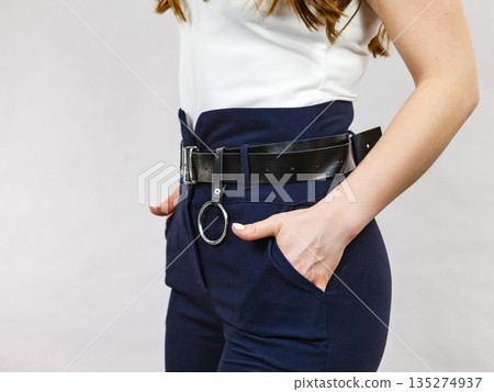 Woman wearing high waist trouser with belt Woman wearing high waist trouser with belt 135274937