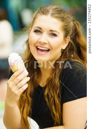 Young woman eating ice cream 135274952