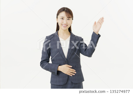 身穿西裝的年輕日本女性，舉起雙手，看向鏡頭，背景為白色，擺姿勢。 135274977