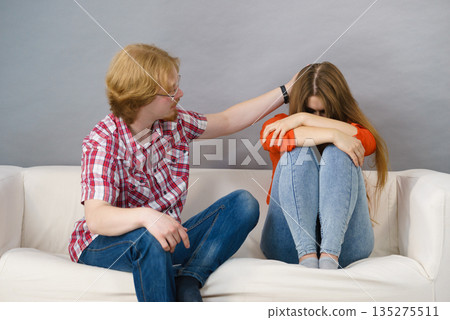 Woman confiding to man on sofa 135275511