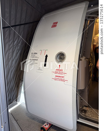 Open aircraft exit door with safety markings. Aviation procedure, passenger boarding, and transport security through cabin entrance detail 135275614