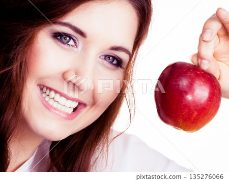 Woman holds apple fruit close to face, isolated Woman holds apple fruit close to face, isolated 135276066