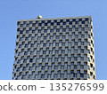 Modern Skyscraper Facade with Checkerboard Pattern Against Blue Sky 135276599