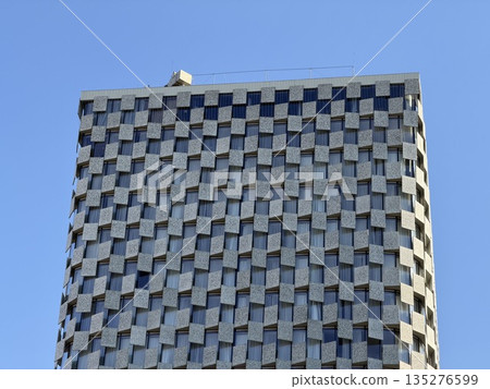 Modern Skyscraper Facade with Checkerboard Pattern Against Blue Sky 135276599