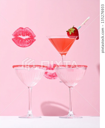 A cold martini glass with a red cherry and two glasses of champagne create a celebratory alcoholic beverage display featuring pink liquid and fresh fruit for a party bar setting 135276933