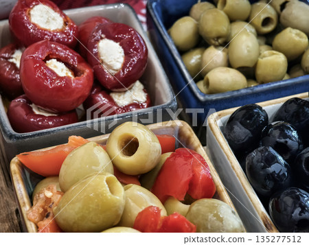 Colorful display of stuffed peppers and assorted olives in small bowls on a wooden table during a casual gathering Colorful display of stuffed peppers and assorted olives in small bowls on a wooden table during a casual gathering 135277512