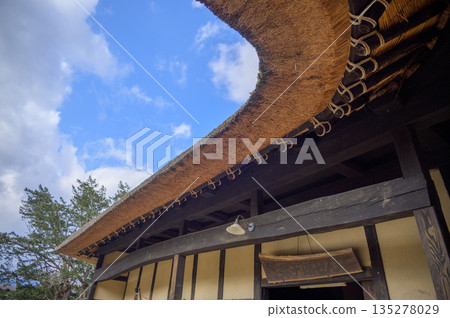 The curved thatched roof of Yajuro-don's Nambu Magari-ya house in Tono Furusato Village in late autumn 135278029