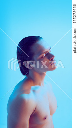 Young man portrait with soft emotional gaze in blue studio. 135278666