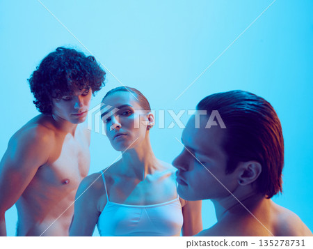 Two men and woman with soft gaze and sculpted skin in blue light. Two men and woman with soft gaze and sculpted skin in blue light. 135278731