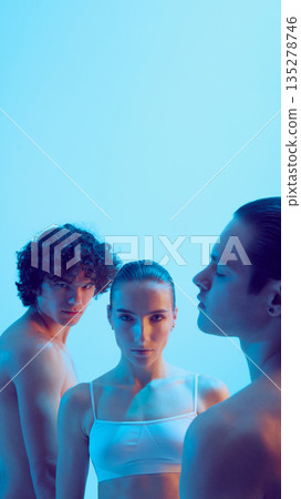 Three young adults with intense gaze in blue studio light. 135278746