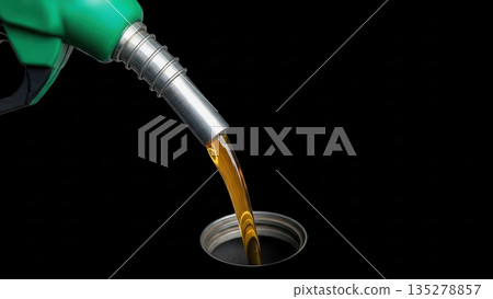 Fuel nozzle dispensing brown liquid into a metallic tank opening, showcasing the process of refueling, with a dark background emphasizing the action and fluid dynamics 135278857