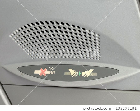 Airplane overhead seat belt sign panel. Inflight instruction, passenger safety, and aircraft regulation through illuminated aviation symbols 135279191
