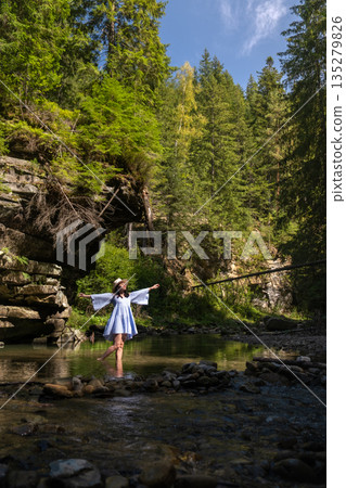 Woman Strolling by River in Forest 135279826