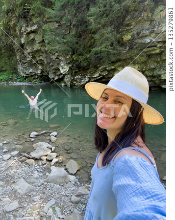 Woman Taking Selfie by River with Swimmer 135279861