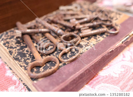 Antique flea market in Europe, Italy. Vintage items. Set of rusty iron keys on book in town. Retro items for background decoration. 135280182