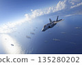 A cutting-edge fighter jet flies over an aircraft carrier strike group. 135280202