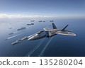 A cutting-edge fighter jet flies over an aircraft carrier strike group. 135280204