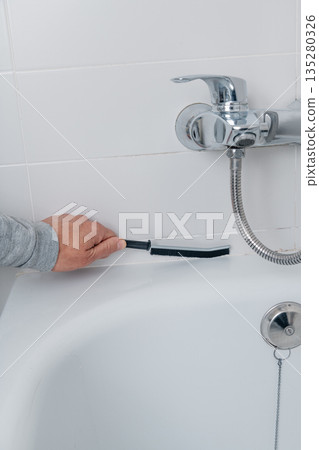 closeup of a man cleaning bathtub tiles closeup of a man cleaning bathtub tiles 135280326