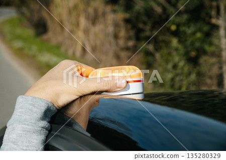 a man places a V16 warning beacon on his car roof a man places a V16 warning beacon on his car roof 135280329