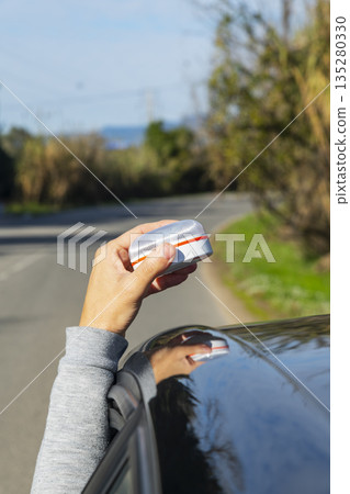 man lifts a V16 warning beacon above the car roof man lifts a V16 warning beacon above the car roof 135280330