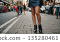 A woman in a miniskirt walking down a busy street 135280461
