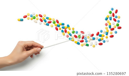 Hand gently arranging colorful pills and capsules on a clean white surface, creating a vibrant wave pattern, illustrating the concept of health and wellness 135280697