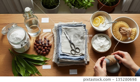 Hands of a woman engaged in crafting with natural materials, surrounded by scissors, fabrics, and bowls of ingredients, showcasing a creative and sustainable lifestyle concept 135280698