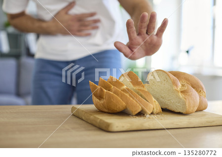 Man with stomach pain refusing bread due to gluten intolerance and diarrhea risk 135280772