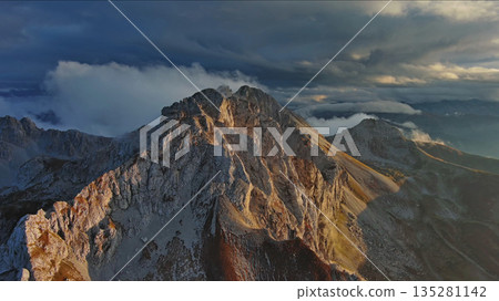 Amazing rocky mountains in clouds at sunset Amazing rocky mountains in clouds at sunset 135281142