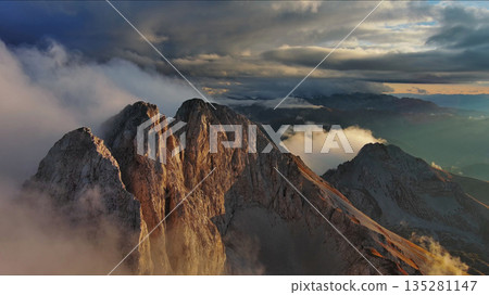 Amazing rocky mountains in clouds at sunset Amazing rocky mountains in clouds at sunset 135281147