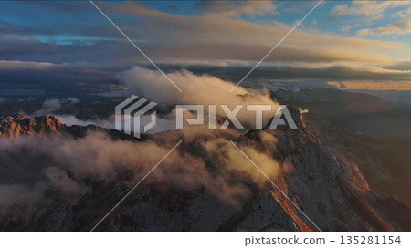 Amazing rocky mountains in clouds at sunset Amazing rocky mountains in clouds at sunset 135281154