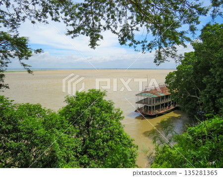 View of trees and a boat on the banks of the Irrawaddy River in Myanmar View of trees and a boat on the banks of the Irrawaddy River in Myanmar 135281365