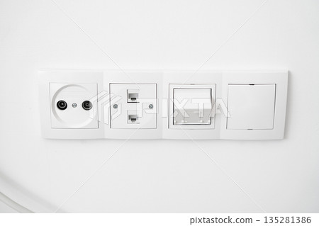 Wall-mounted electrical outlets and network sockets on white wall, modern home installation with power, TV and internet connections 135281386