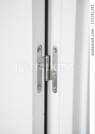 Close-up of metal door hinge on white interior door, modern home hardware detail, minimalist architecture and residential construction concept Close-up of metal door hinge on white interior door, modern home hardware detail, minimalist architecture and residential construction concept 135281391