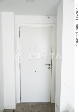 Modern white apartment entry door with peephole and metal handle in clean hallway, minimalist interior security concept 135281398