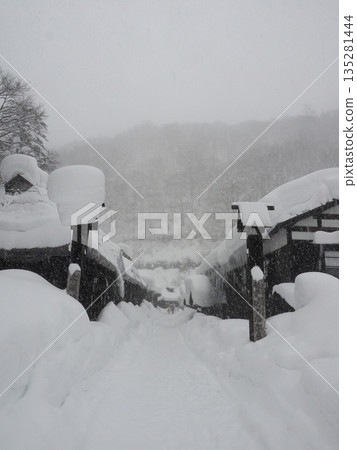 在暴風雪肆虐的山區村莊，一座傳統的日式房屋被厚厚的積雪掩埋，能見度極低。 135281444