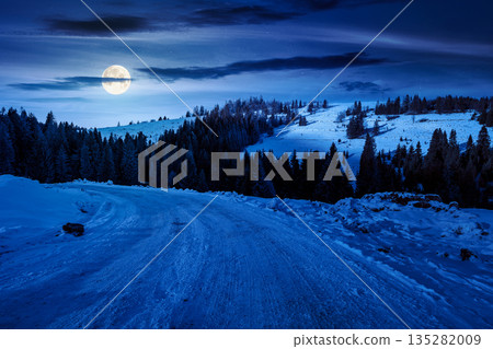 winter landscape with snow covered country road winding through fir forest in mountains at night. alpine countryside of in full moon light. inner strength to overcome fear, loneliness in darkness winter landscape with snow covered country road winding through fir forest in mountains at night. alpine countryside of in full moon light. inner strength to overcome fear, loneliness in darkness 135282009