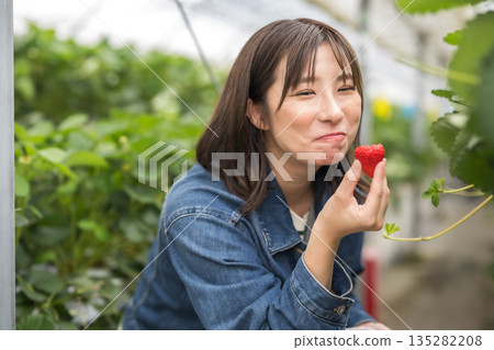 A woman holding a strawberry with a smile 135282208